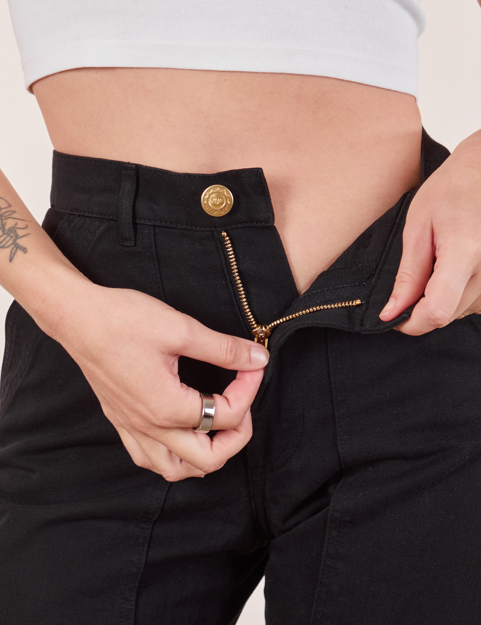 Pencil Pants in Basic Black front close up with Alex pulling on the zipper tab.