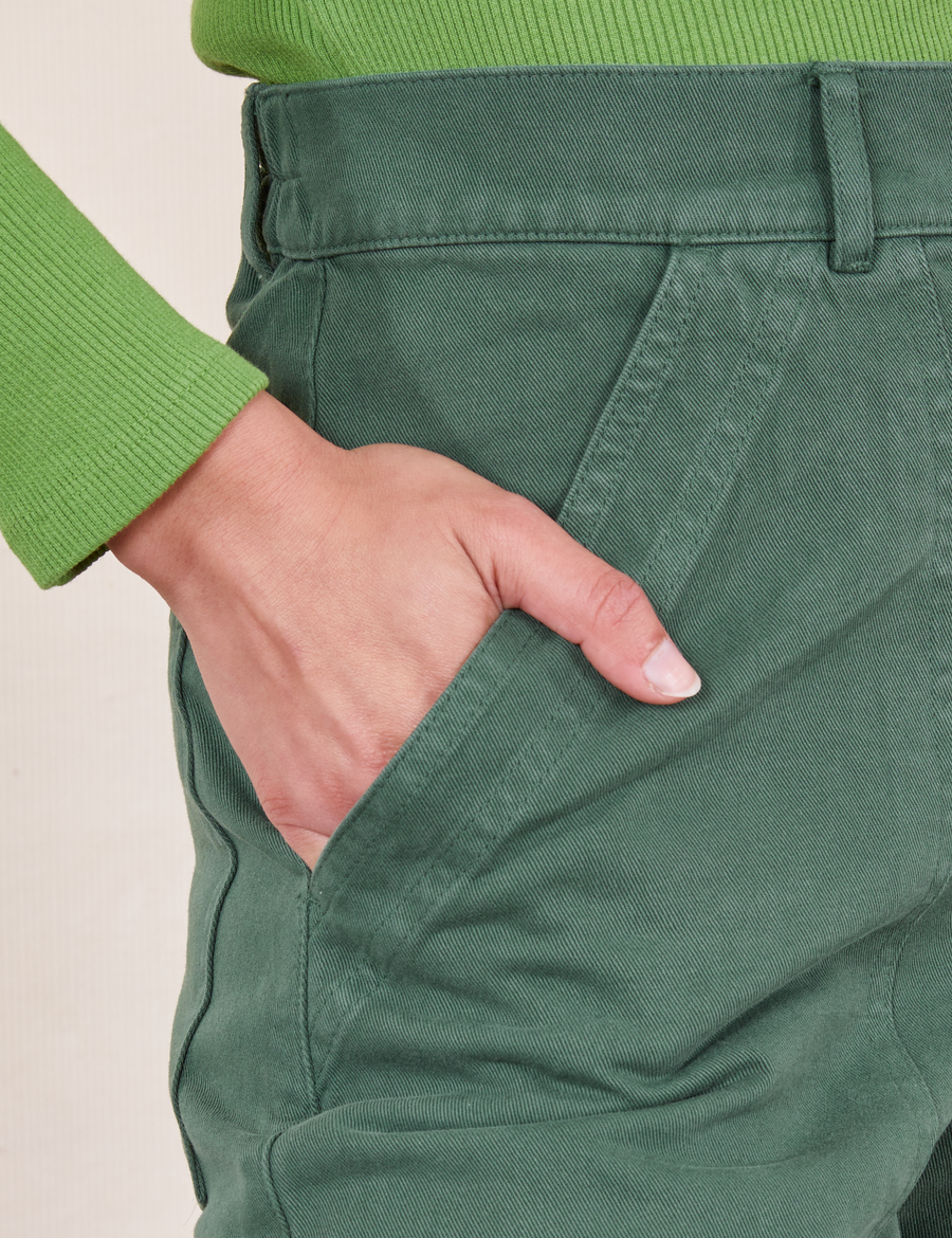 Front close up of Pencil Pants in Dark Emerald Green. Worn by Soraya with her hand in the pocket.