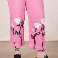 Pant leg close up of California Poppy Overalls in Bubblegum Pink. Paintstamped white poppies with black stems and leaves along the bottom of pant.