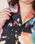 Front close up of Petite Short Sleeve Jumpsuit in Rainbow Magic Waters. Ashley is holding onto the collar.