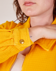 Ricky Jacket in Sunshine Yellow sleeve close up worn by Alex. Custom sun baby brass button on cuff.