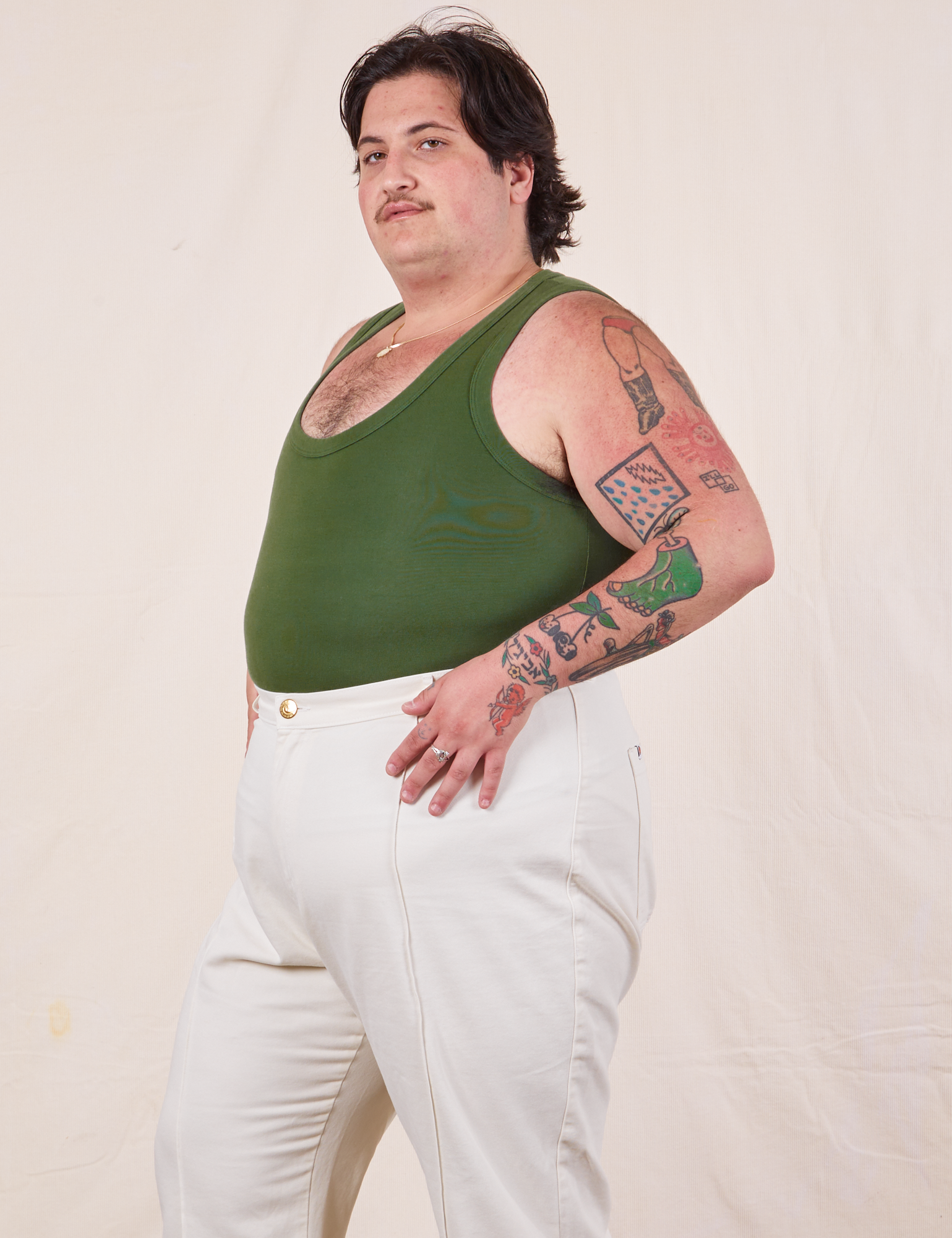 Angled view of Tank Top in Dark Emerald Green and vintage off-white Western Pants worn by Sam
