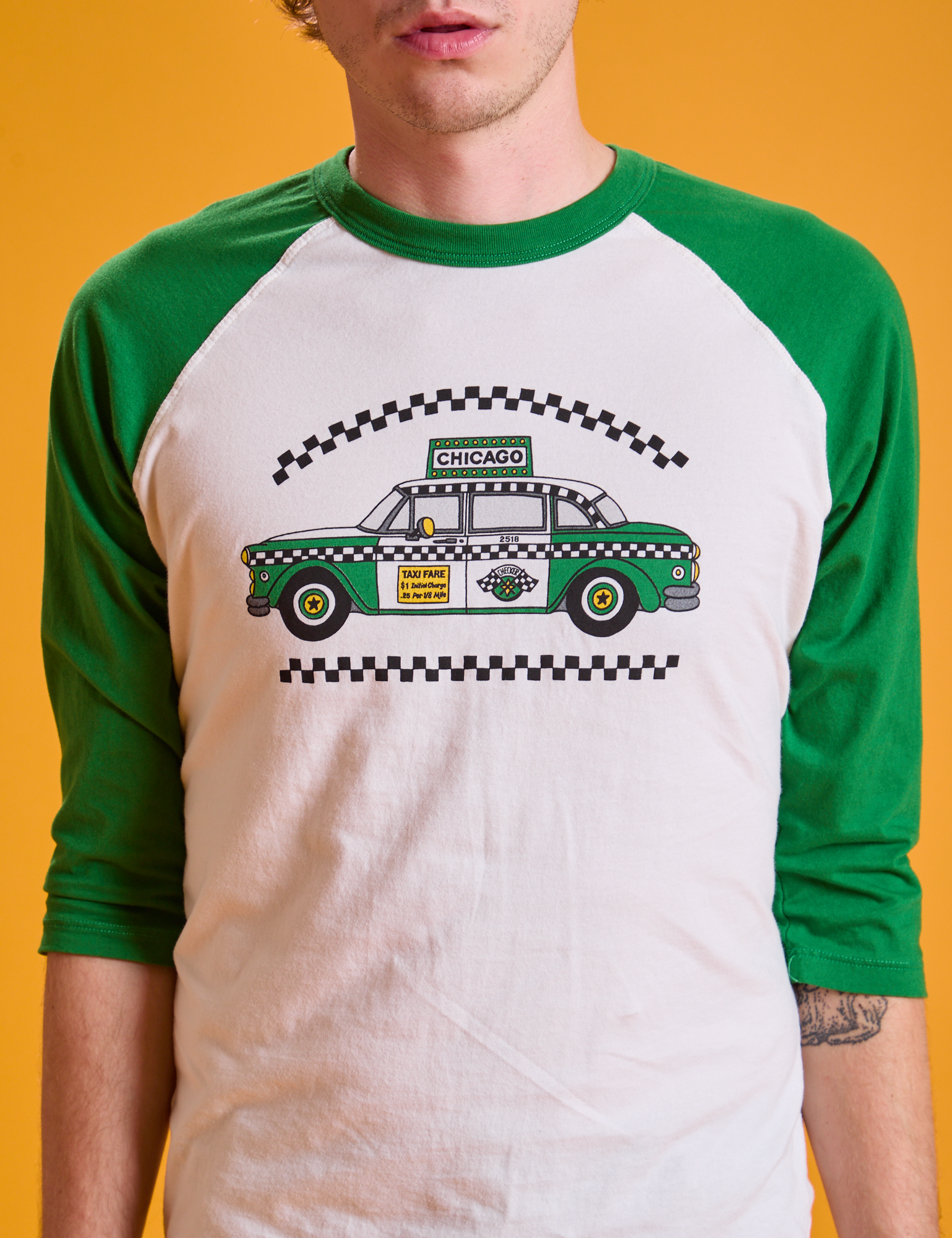 Taxi Raglan Tee in Chicago front close up on Quinn. White tee body and green raglan sleeves