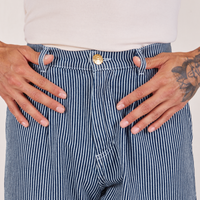 Front close up of Denim Trouser Jeans in Railroad Stripe. Jesse has their thumbs through the belt loops