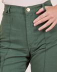 Front close up of Western Pants in Dark Green Emerald. Alex has her thumb in one of the belt loops
