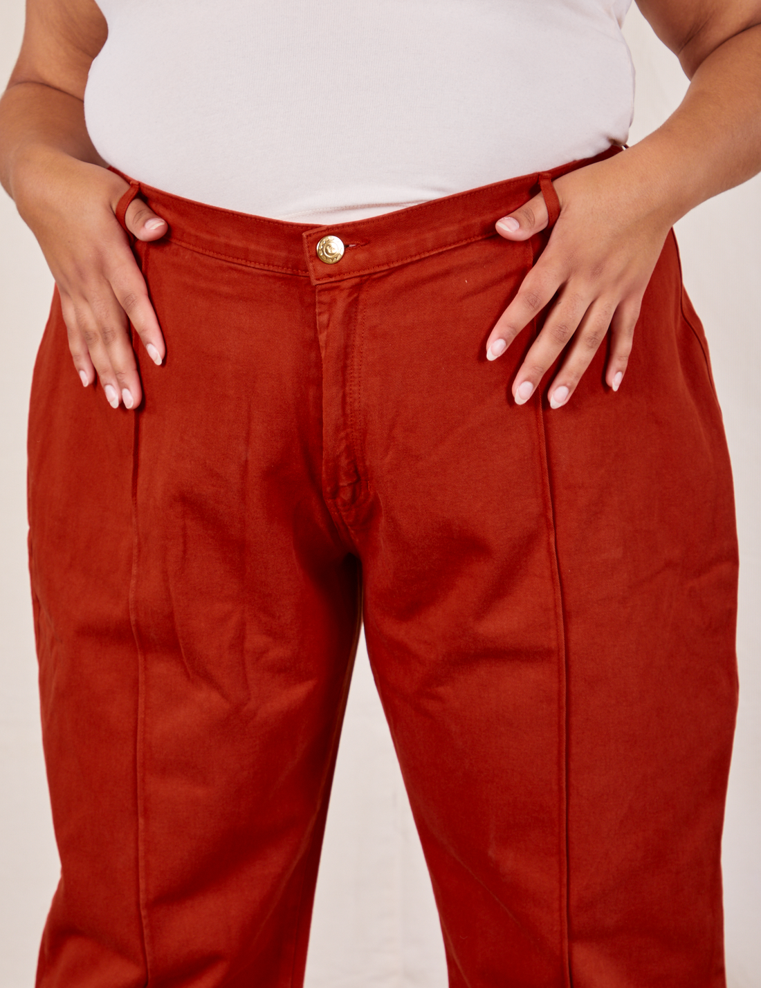 Front close up of Western Pants in Paprika. Alicia has both her thumbs through the belt loop