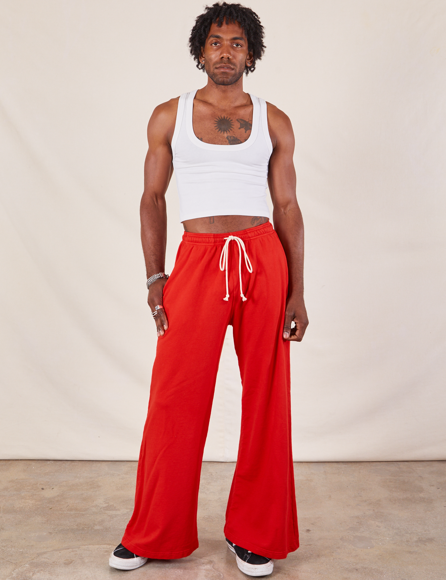 Jerrod is wearing Wide Leg Sweat Pants in Mustang Red and Cropped Tank in vintage tee off-white