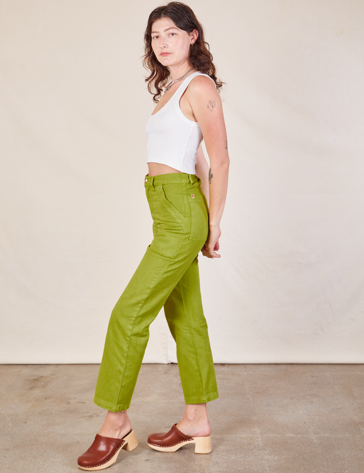 Side view of Work Pants in Gross Green and Cropped Tank in vintage tee off-white on Alex