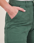 Front pocket close up of Work Pants in Dark Emerald Green. Worn by Soraya with her hand in the pocket.