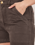 Classic Work Shorts in Espresso Brown front pocket close up. Tiara has her hand in the pocket.