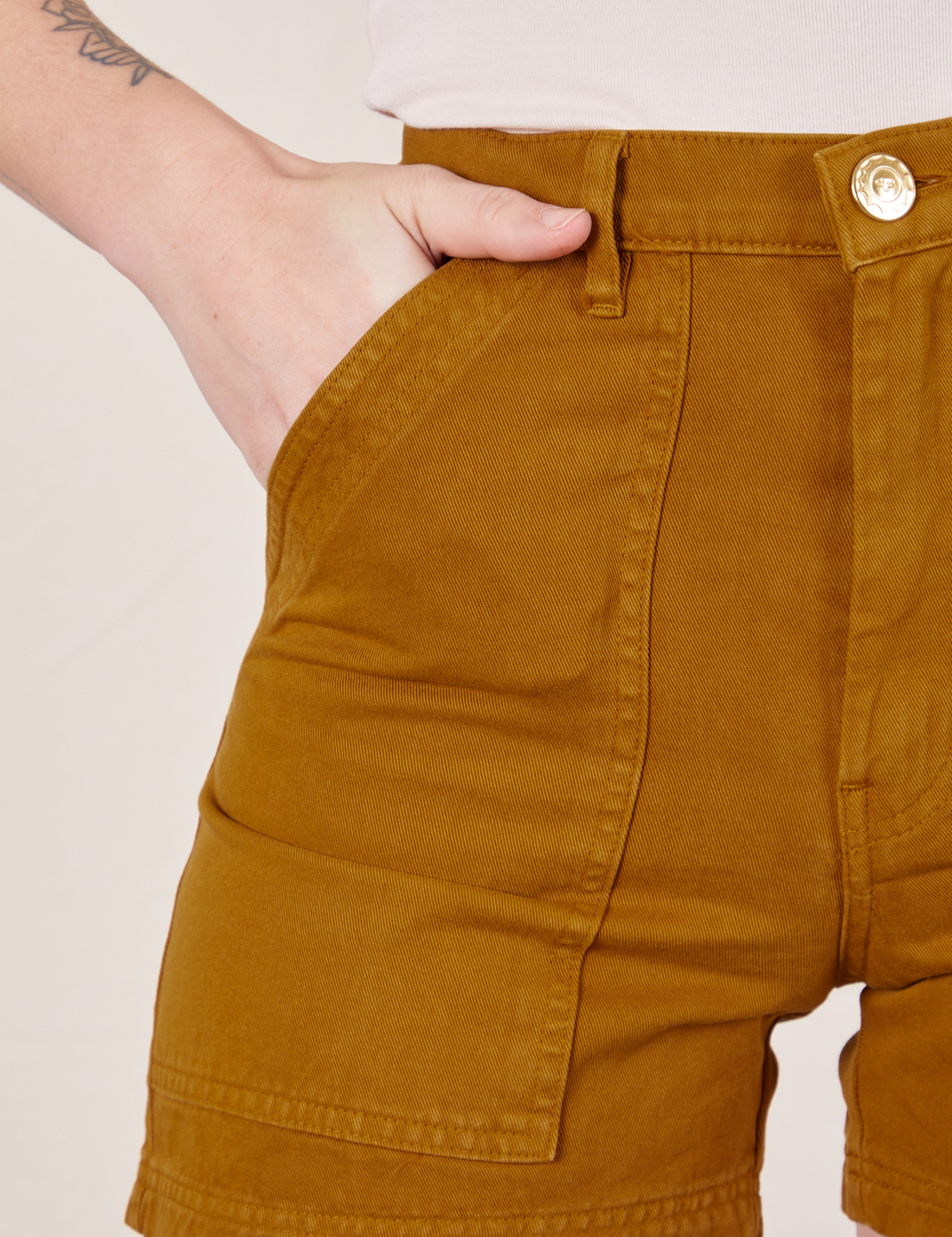 Classic Work Shorts in Spicy Mustard front close up. Alex has her hand in the pocket.