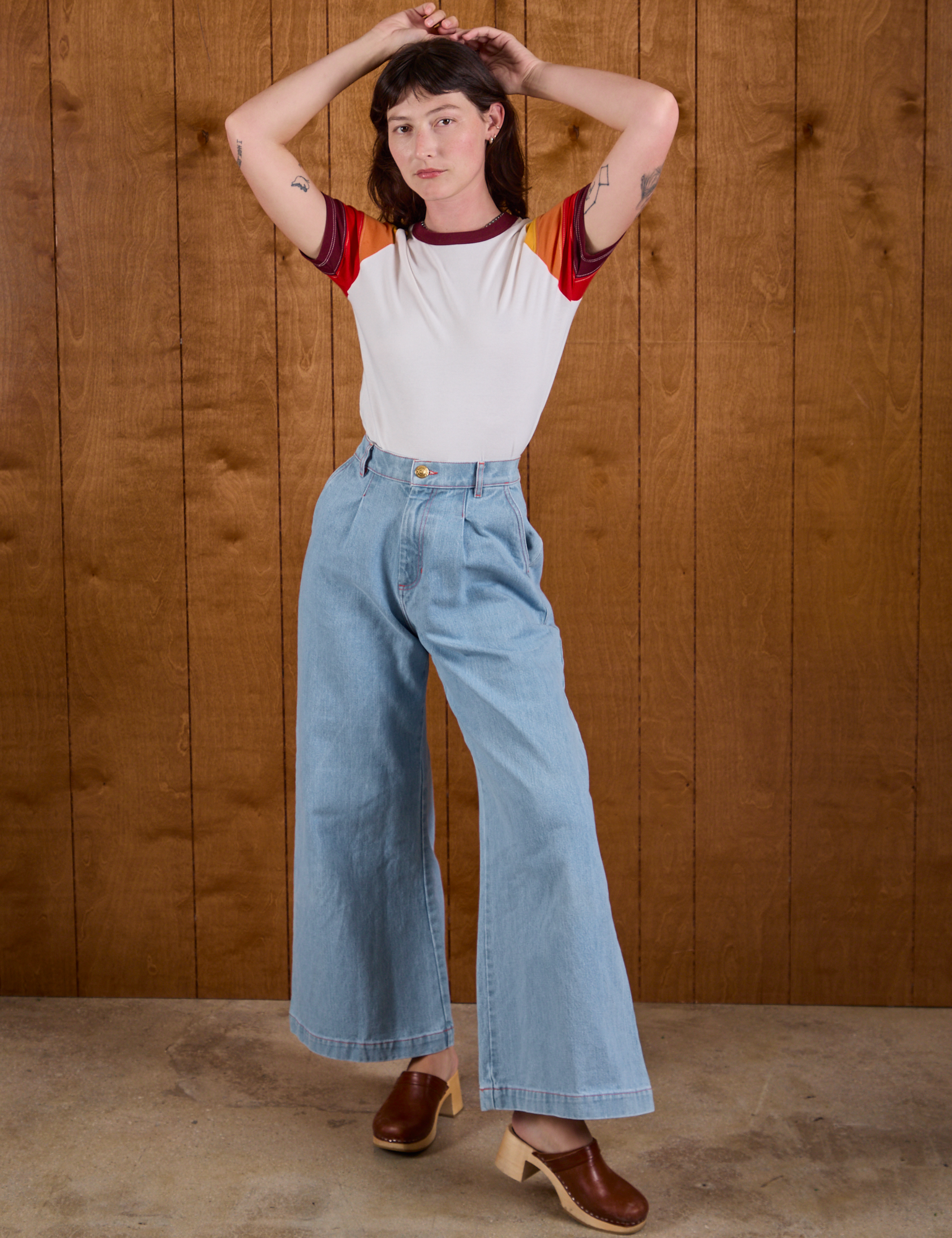 Alex is wearing Calypso Tee in Desert and light wash Indigo Wide Leg Trousers