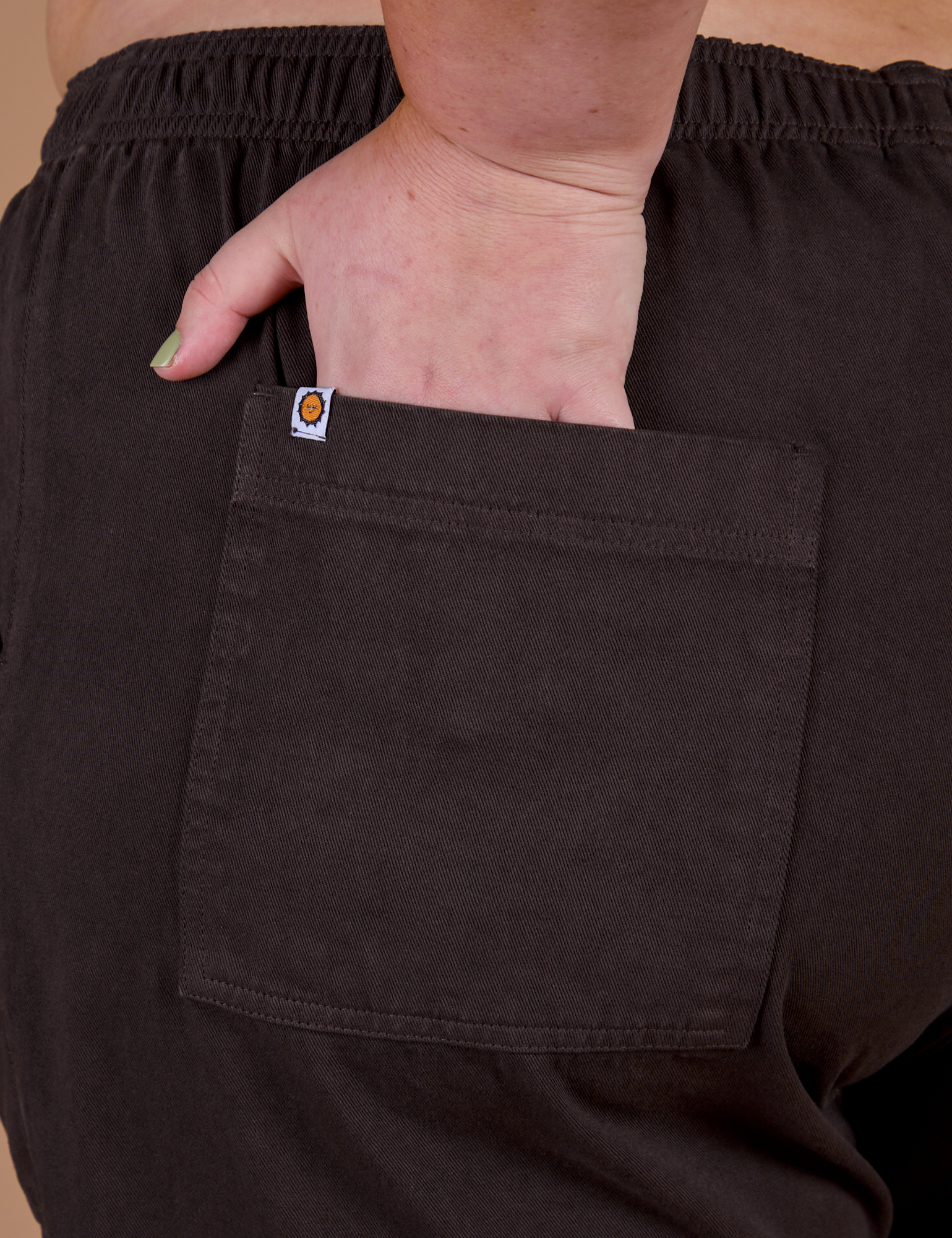 Close up of Juliet's hand in the back pocket of Action Pants in Espresso Brown