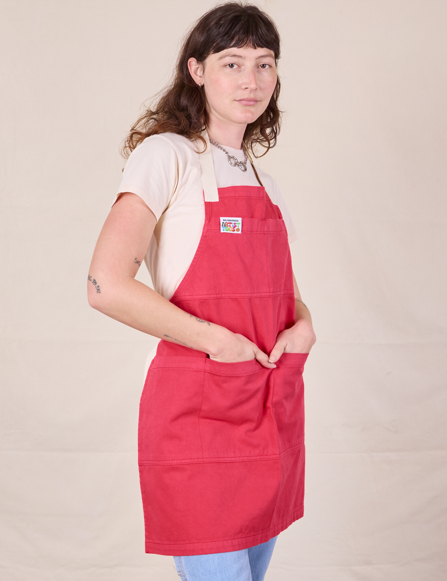 Angled view of Full Denim Apron in Hot Pink worn by Alex