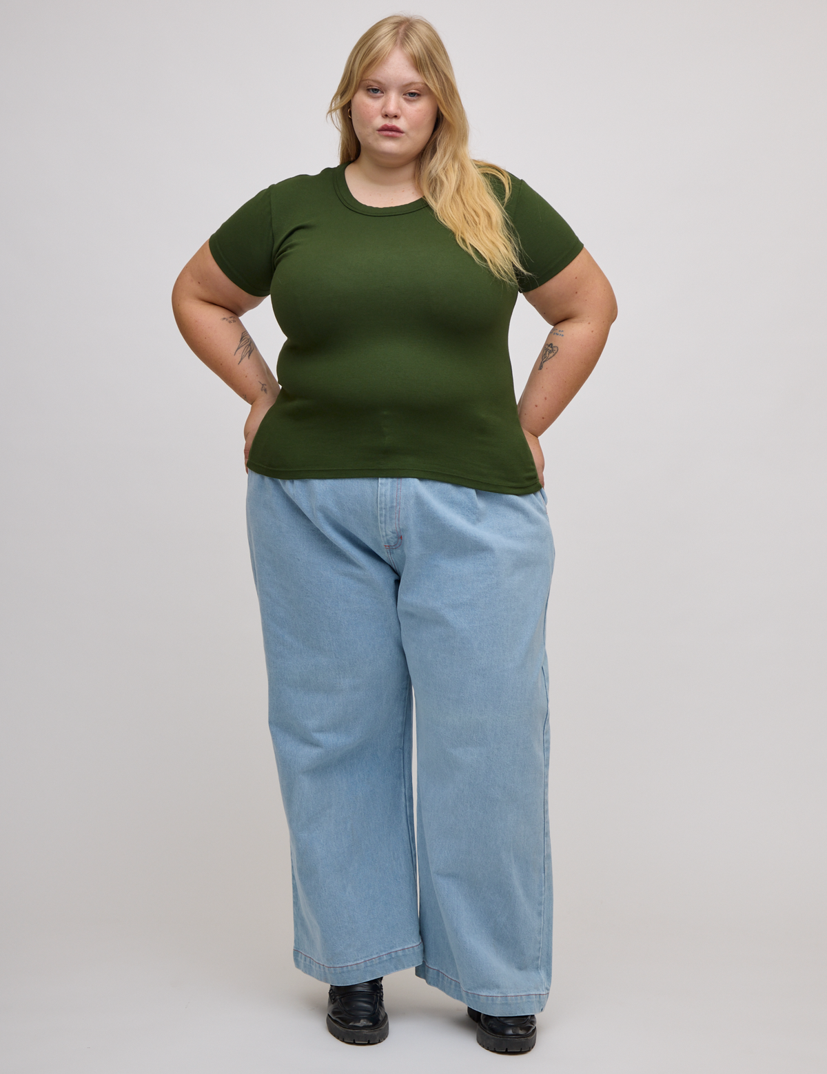 Juliet is wearing Baby Tee in Evergreen and light wash denim wide leg trousers