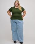 Juliet is wearing Baby Tee in Evergreen and light wash denim wide leg trousers