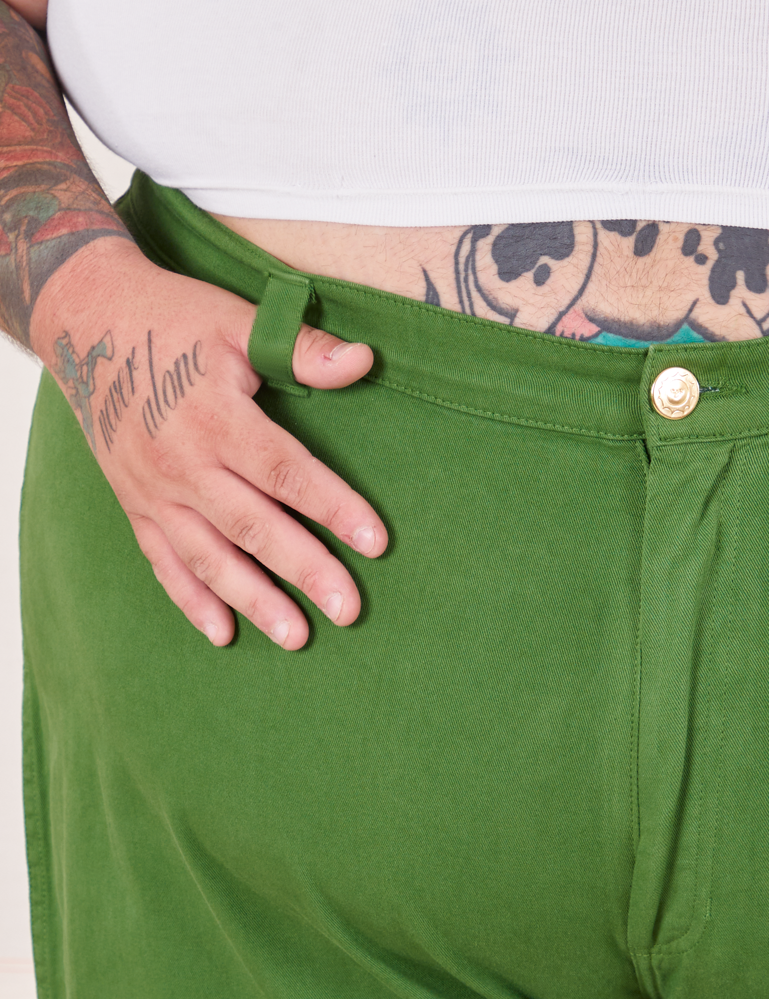 Bell Bottoms in Lawn Green front close up. Sam has their thumb in the belt loop.