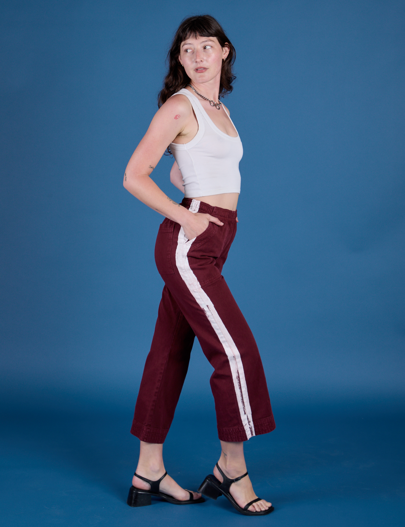 Side view of Painted Action Pants in Red Wine and vintage tee white Cropped Tank on Alex