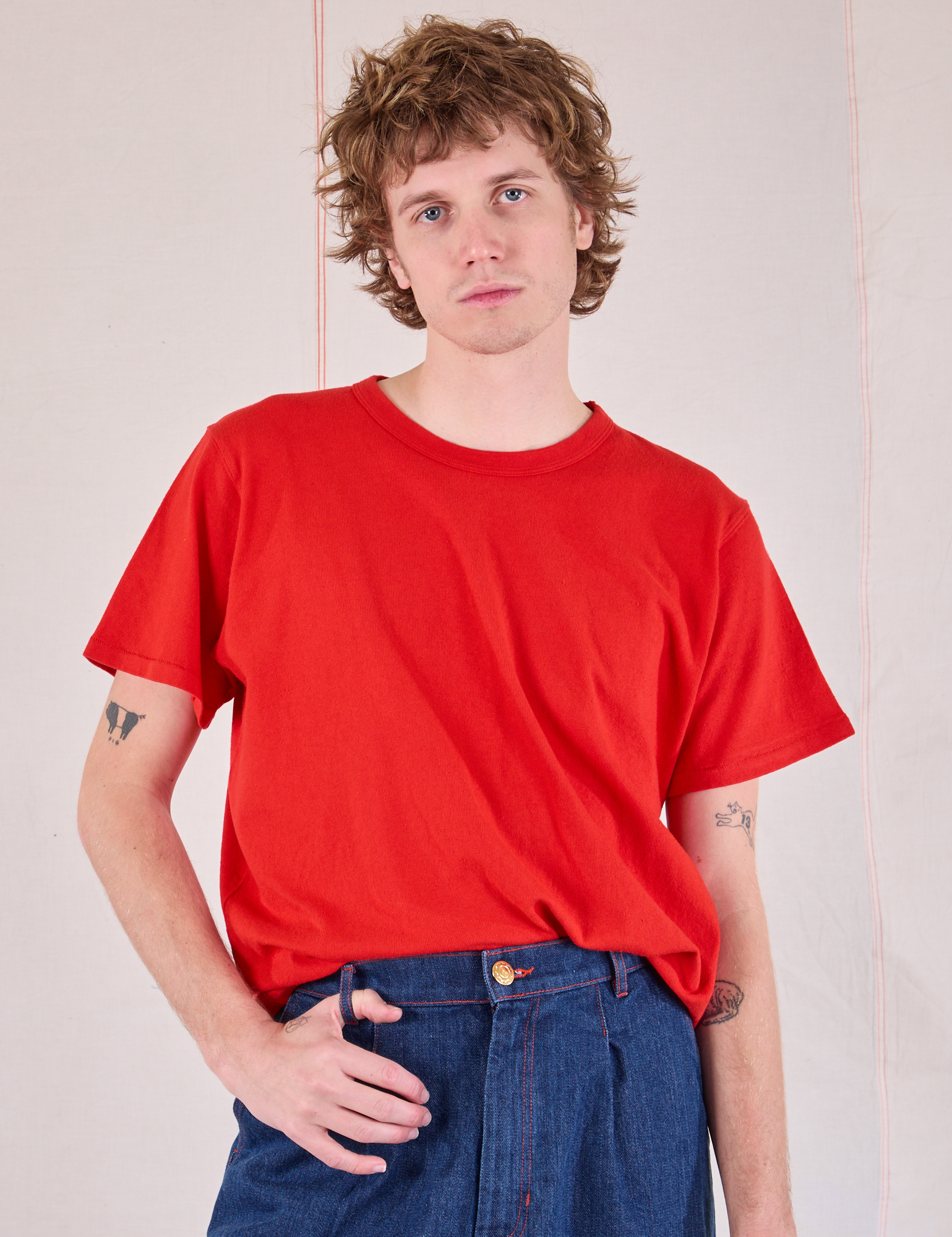 Quinn is wearing Burly Tee in Mustang Red tucked into dark wash Denim Trousers