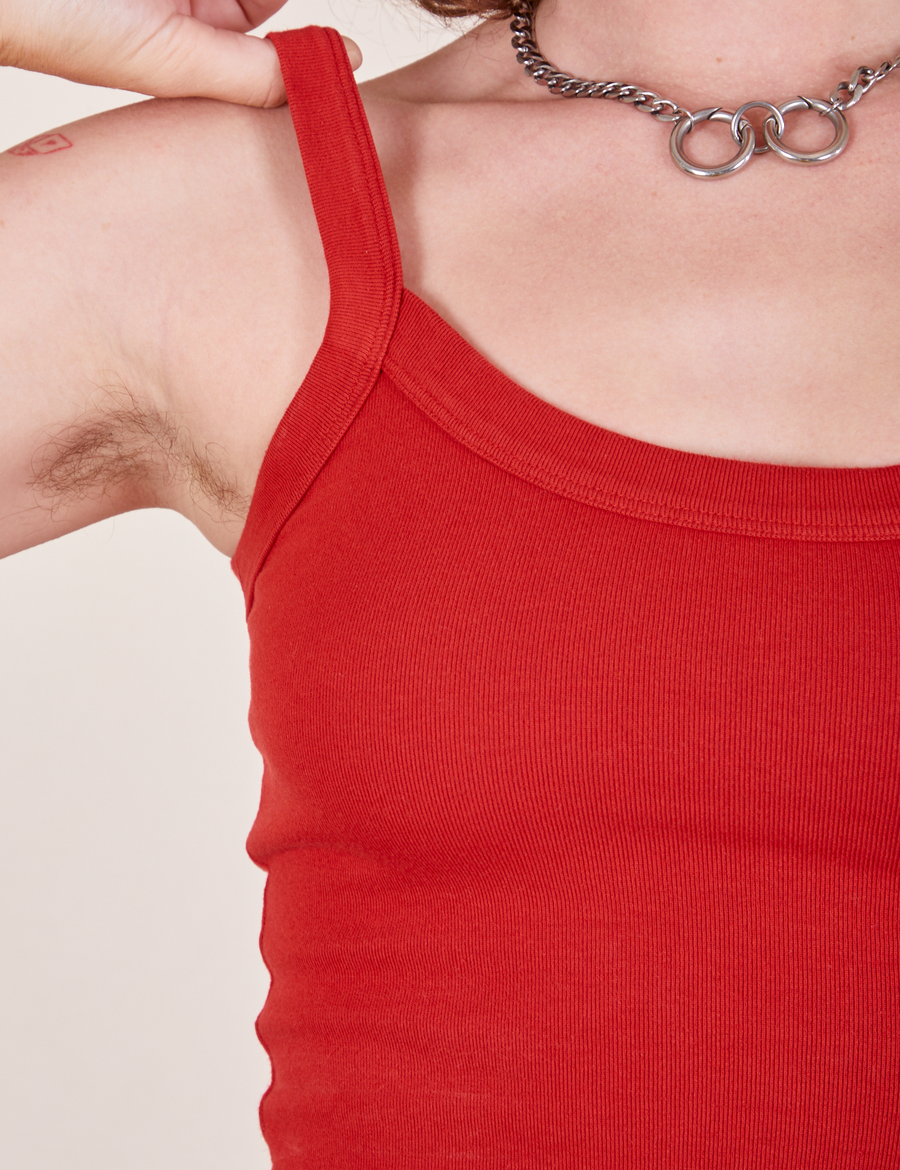 Neckline and strap close up of Cropped Cami in Mustang Red worn by Alex. She has her thumb underneath one of the tank straps.