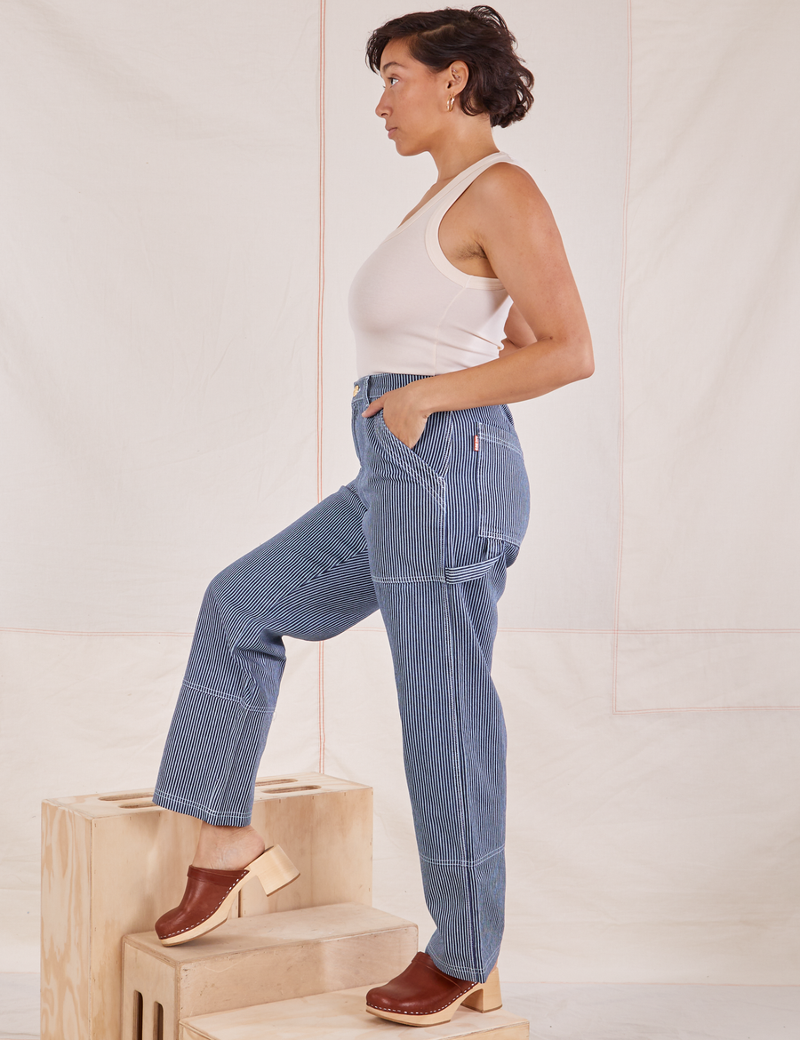 Side view of Carpenter Jeans in Railroad Stripes and vintage off-white Tank Top worn by Tiara