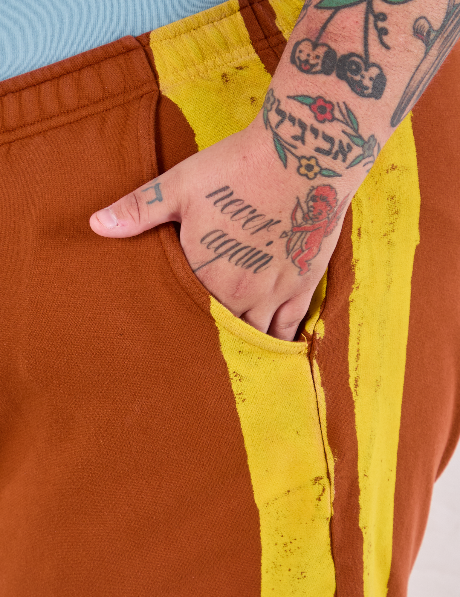 Close up of Sam&#39;s hand in the pocket of Painted Stripe Easy Shorts in Burnt Terracotta