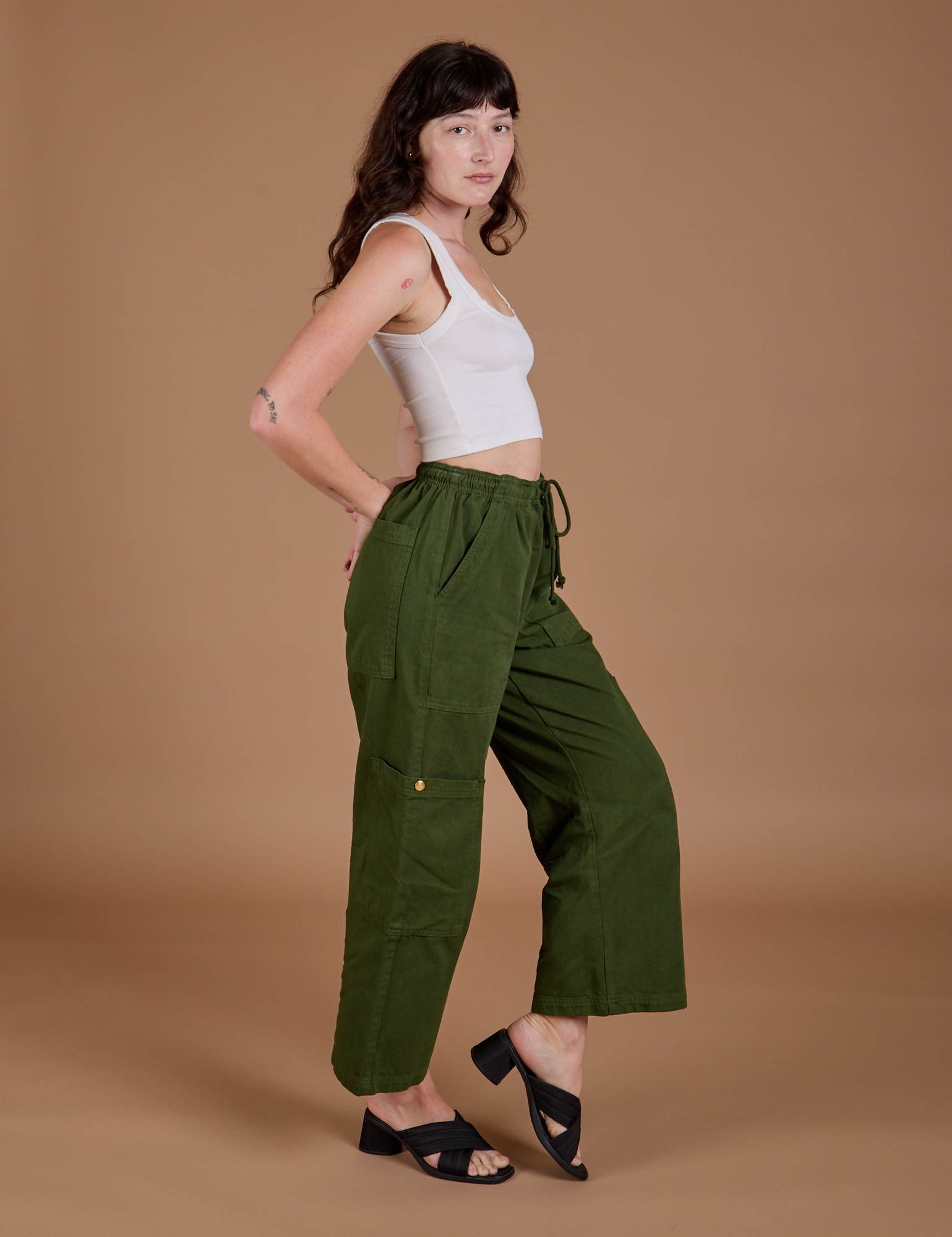 Side view of Drop Pocket Cargo Pants in Evergreen and Cropped Tank in vintage tee white on Alex