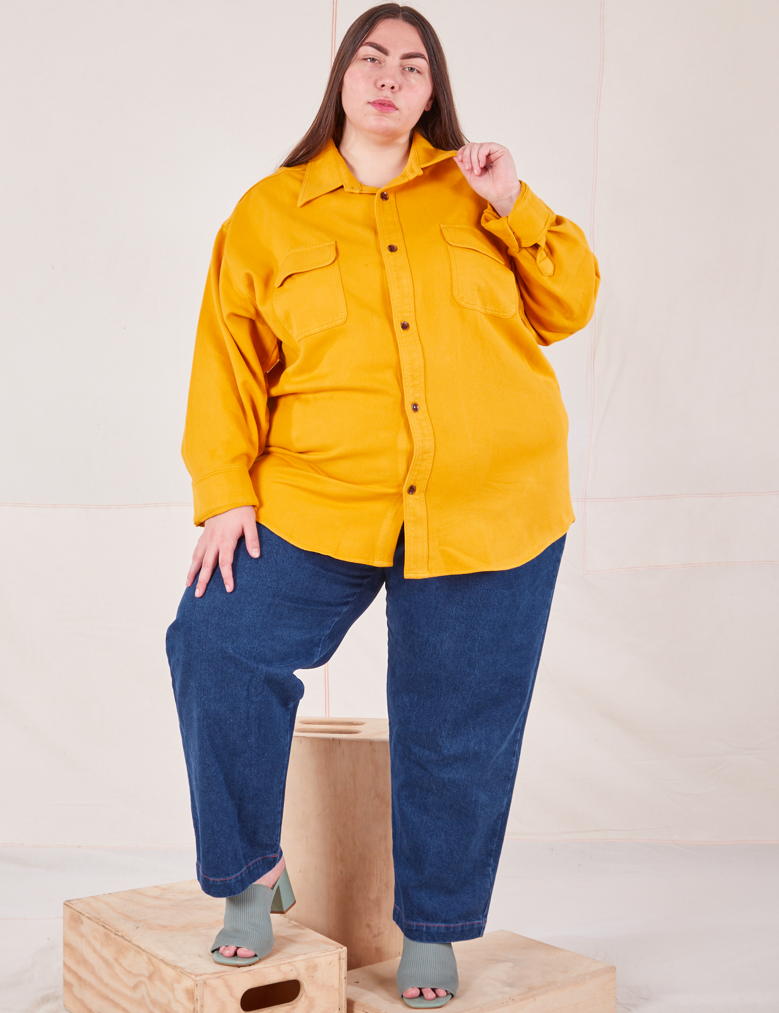 Marielena is wearing a buttoned up Flannel Overshirt in Mustard Yellow paired with dark wash Trouser Jeans