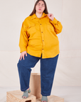 Marielena is wearing a buttoned up Flannel Overshirt in Mustard Yellow paired with dark wash Trouser Jeans