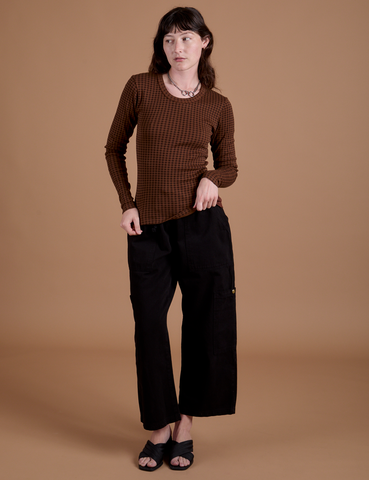 Alex is wearing Gingham Long Sleeve Baby Tee in Fudgesicle Brown and black Drop Pocket Cargo Pants