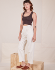 Angled view of Heavyweight Trousers in Vintage Off-White and espresso brown Cropped Tank Top worn by Alex.