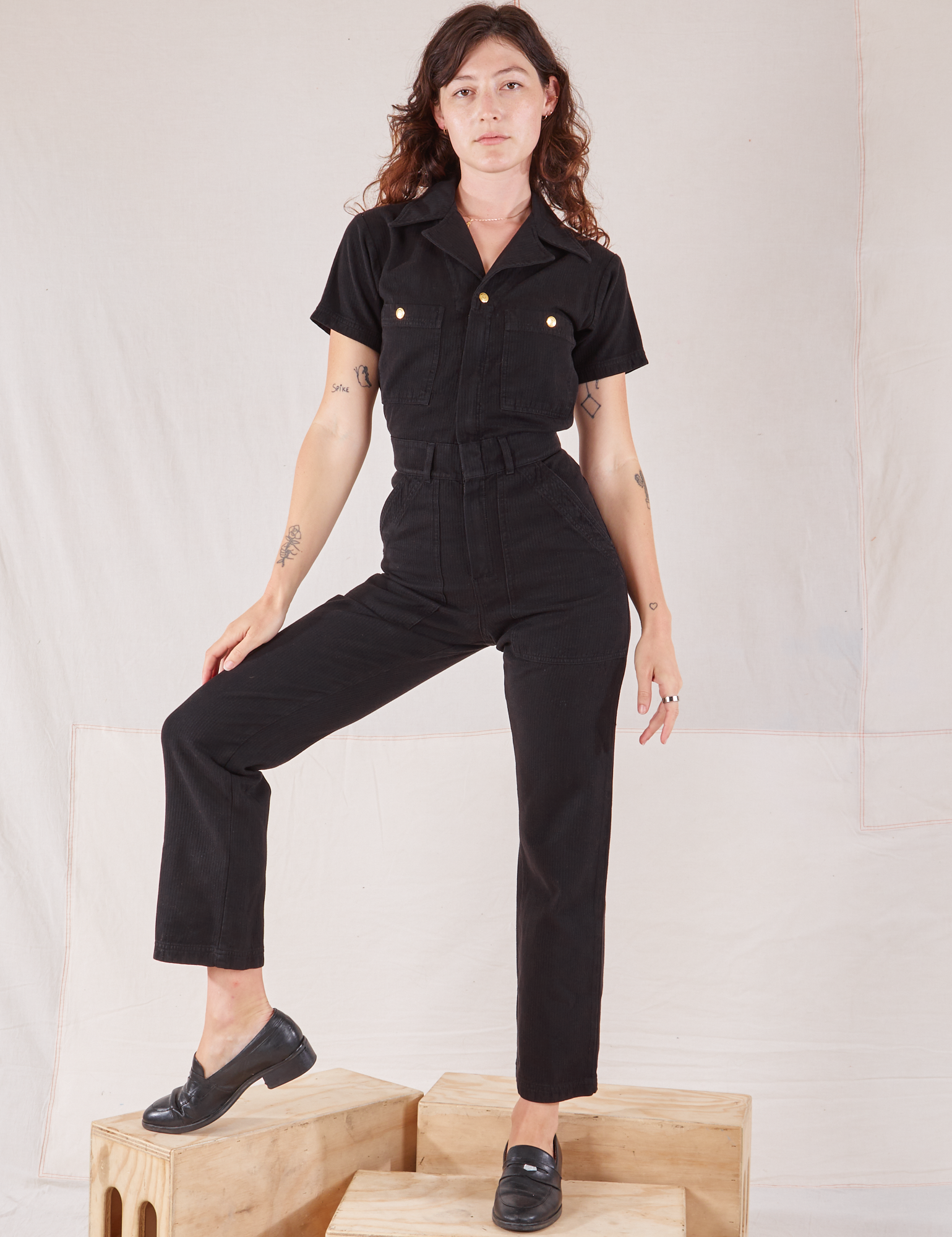 Alex is wearing Heritage Short Sleeve Jumpsuit in Basic Black