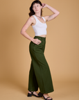 Side view of Heritage Wide Leg Trousers in Evergreen and vintage tee white Cropped Tank
