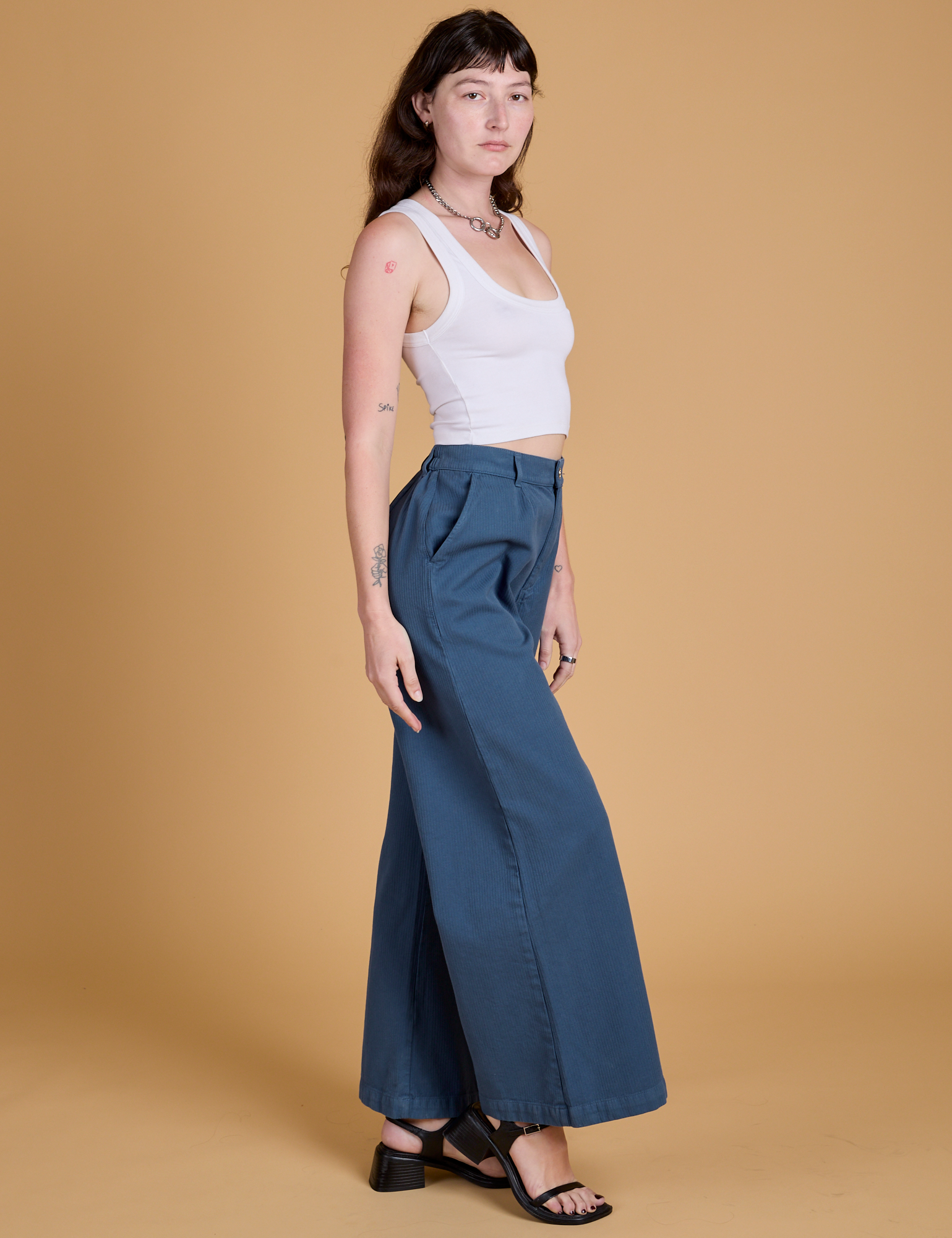 Side view of Heritage Wide Leg Trousers in French Blue and vintage tee white Cropped Tank on Alex