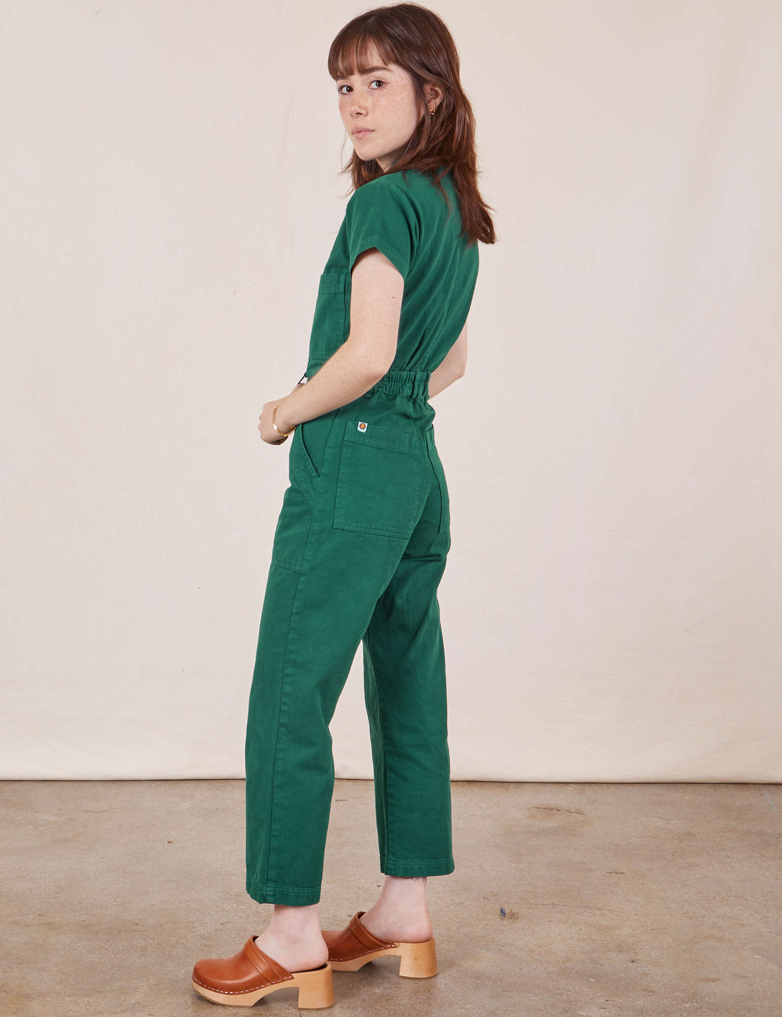 Side view of Petite Short Sleeve Jumpsuit in Hunter Green worn by Hana