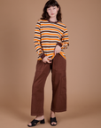 Alex is wearing Long Sleeve Striped Burly Tee in Orange and Drop Pocket Cargo Pants in Fudgesicle Brown