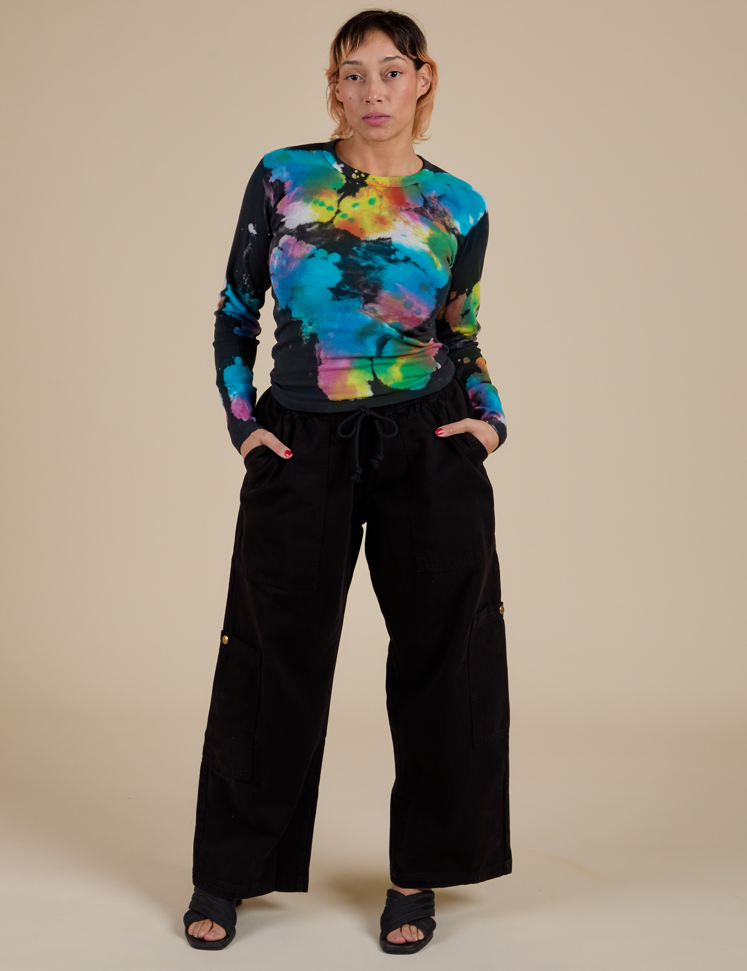 Tiara is wearing Long Sleeve Baby Tee in Rainbow Magic Waters paired with black Dropped Pocket Cargo Pants