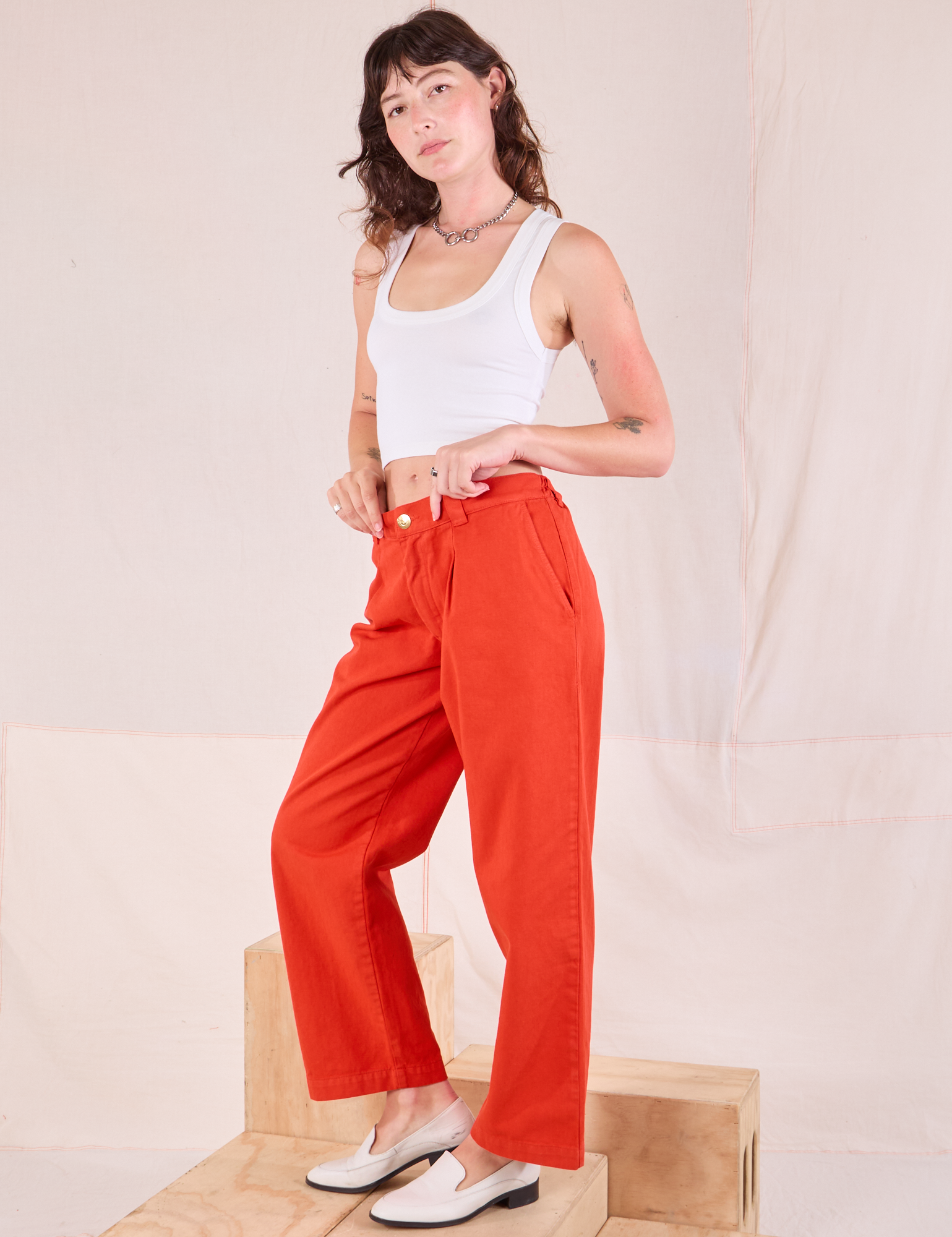 Side view of Mid-Rise Pleated Trousers in Chili Red and Cropped Tank in vintage tee off-white worn by Alex