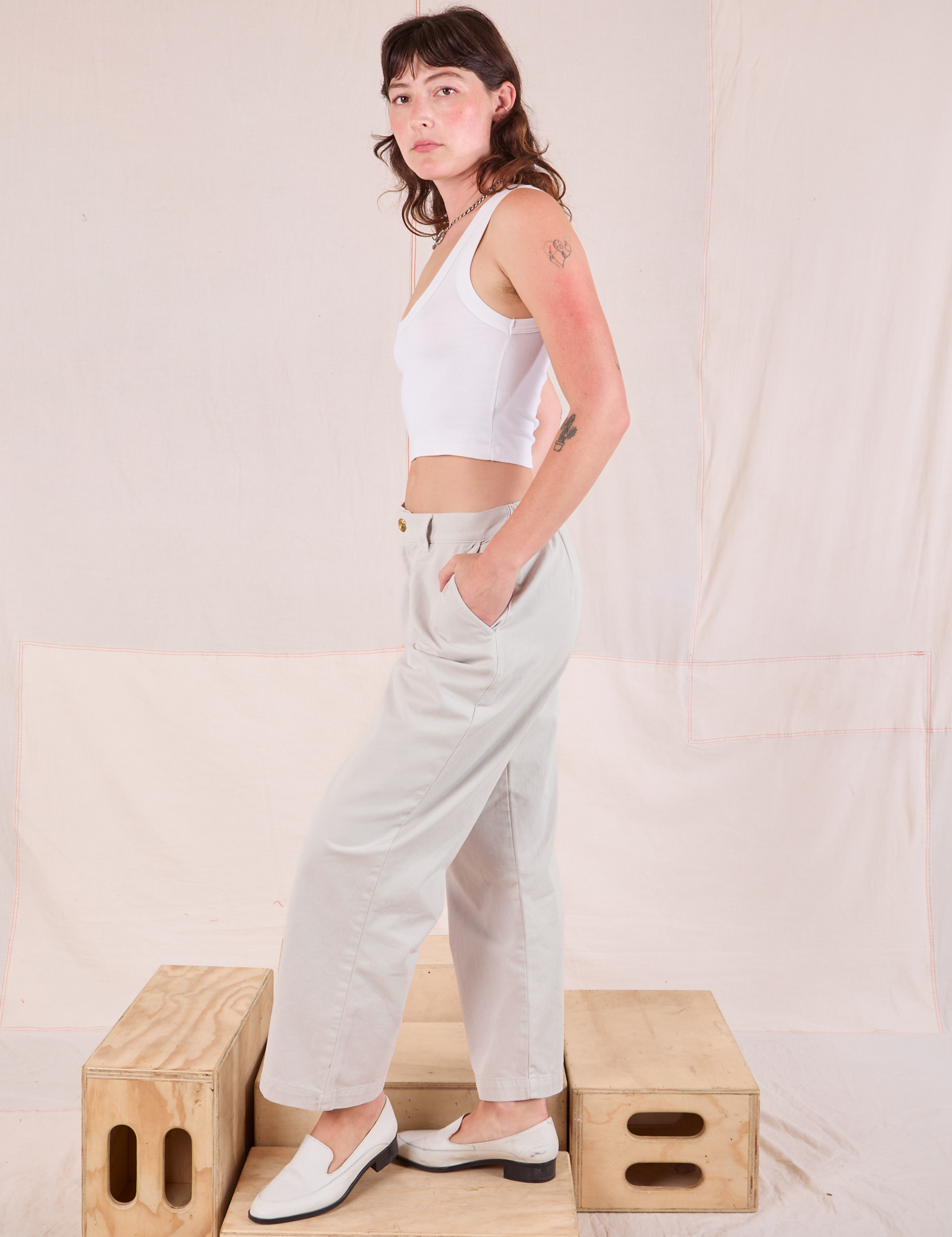 Side view of Mid-Rise Pleated Trousers in Stone White and Cropped Tank in Vintage Tee Off-White on Alex