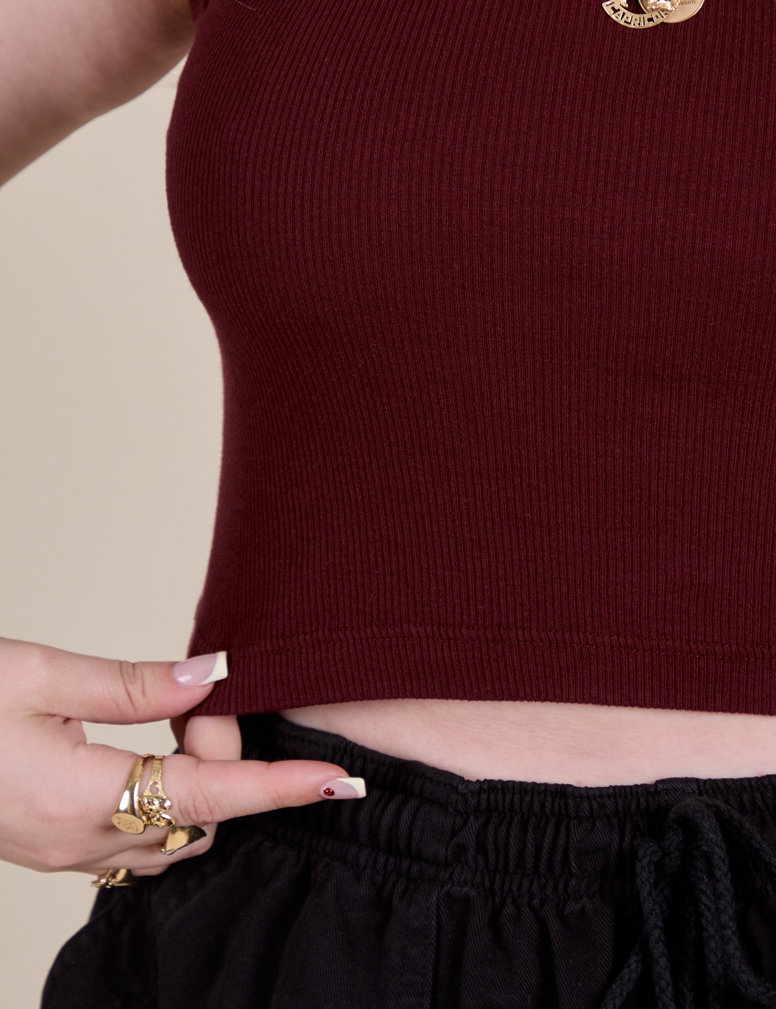 Close up of Sydney holding the bottom hem of Muscle Tee in Red Wine