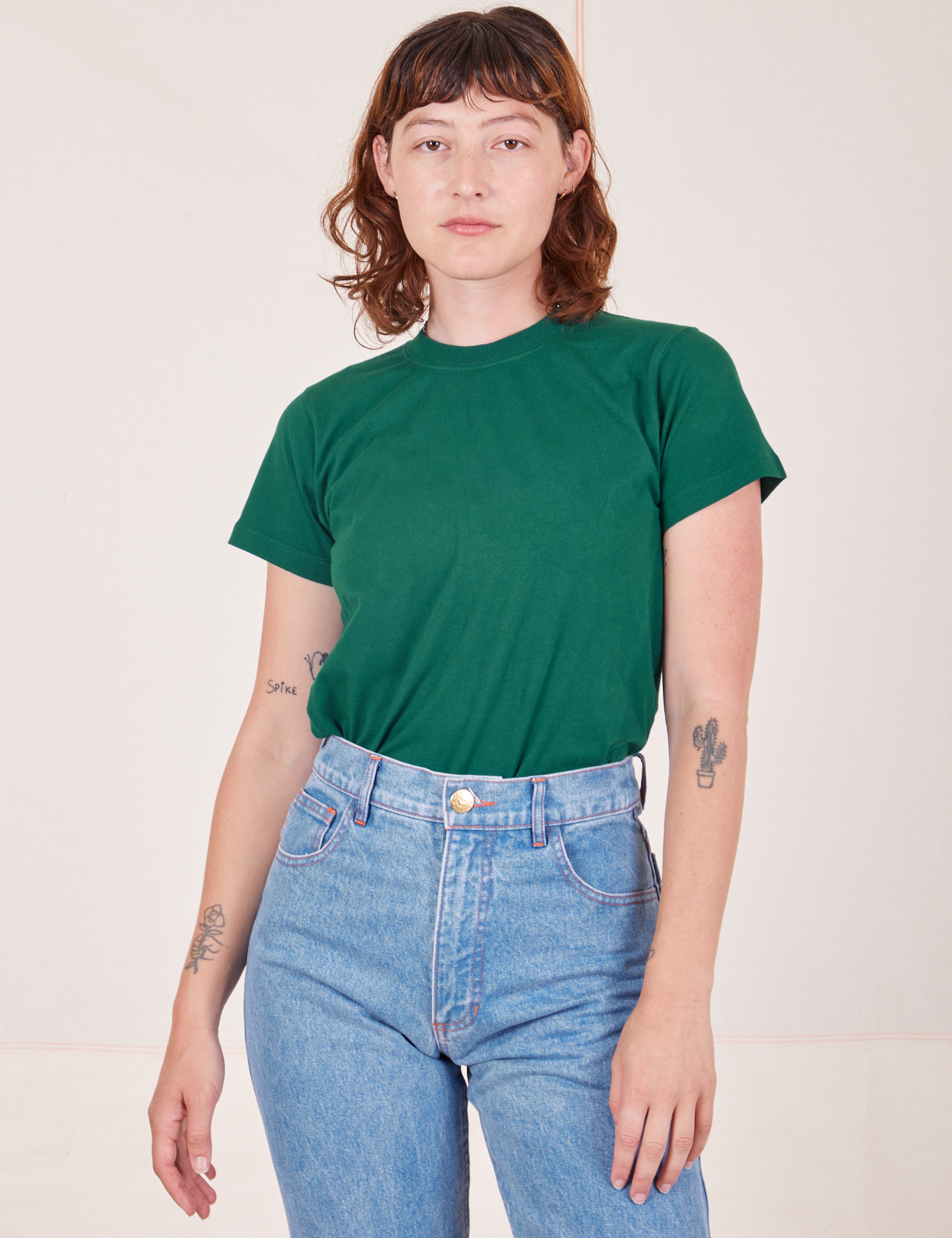 Alex is wearing Organic Vintage Tee in Hunter Green tucked into light wash Frontier Jeans