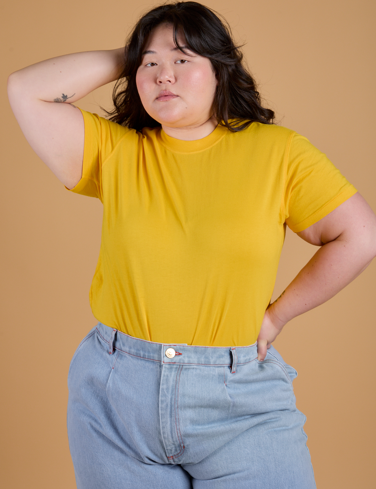 Ashley is wearing  Organic Vintage Tee in Sunshine Yellow tucked into light wash Indigo Wide Leg Trousers