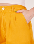 Front pocket close up of Organic Trousers in Mustard Yellow. Alex has her hand in the pocket.