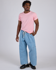 Isaac is wearing Jr. Varsity Tee in Baby Pink paired with light wash Denim Drop Pocket Pants