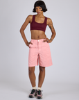 Kira is wearing Longline Work Shorts in Baby Pink and red wine mini Tank