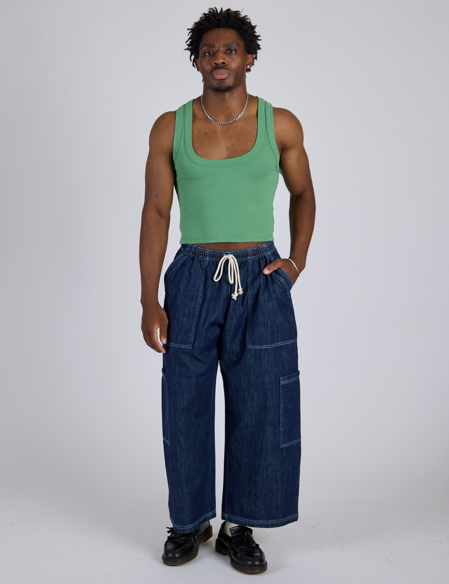 Isaac is wearing Cropped Tank Top in Seafoam Green and dark wash Denim Drop Pocket Pants