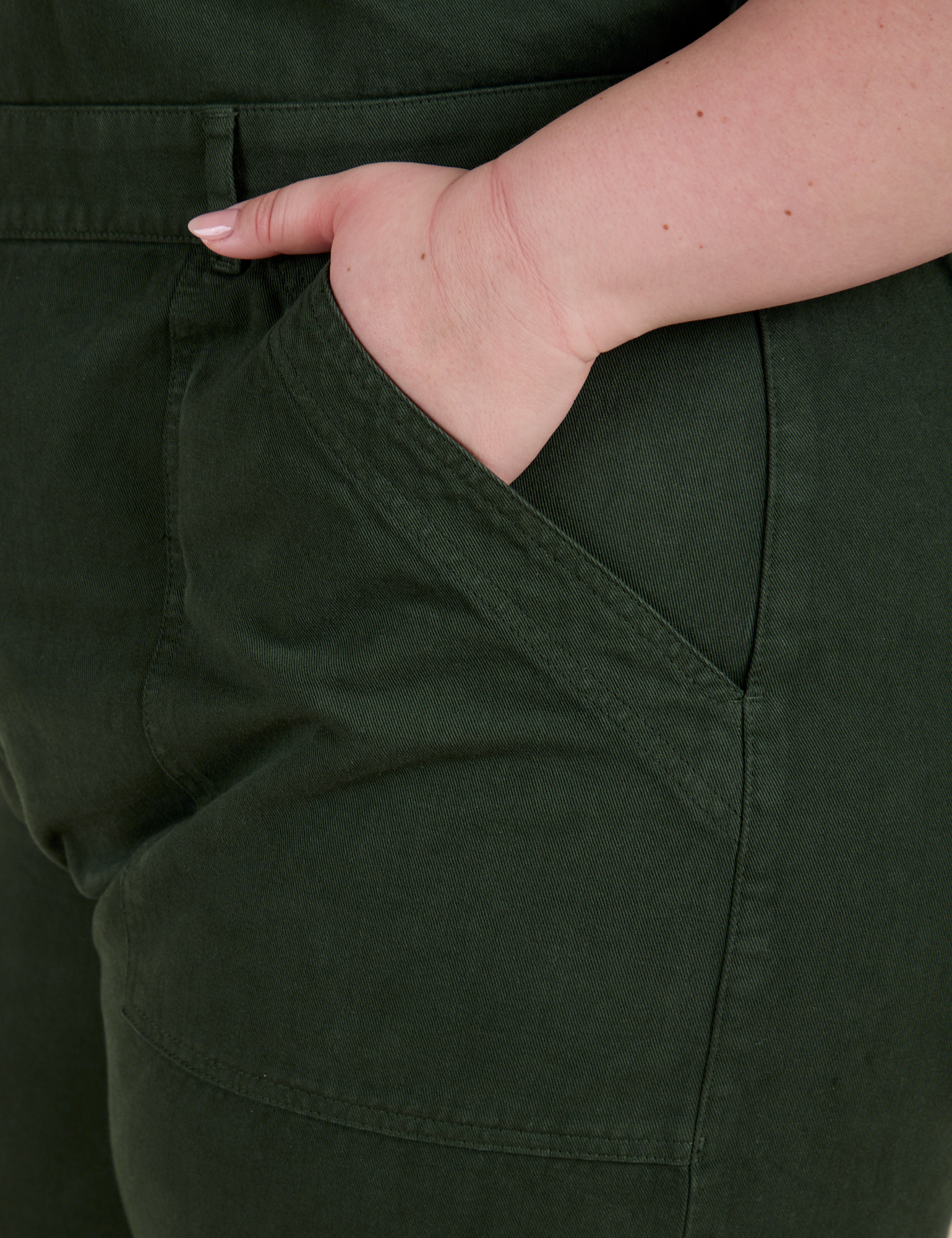 Close up of Ashley's hand in the front pocket of Short Sleeve Jumpsuit in Swamp Green