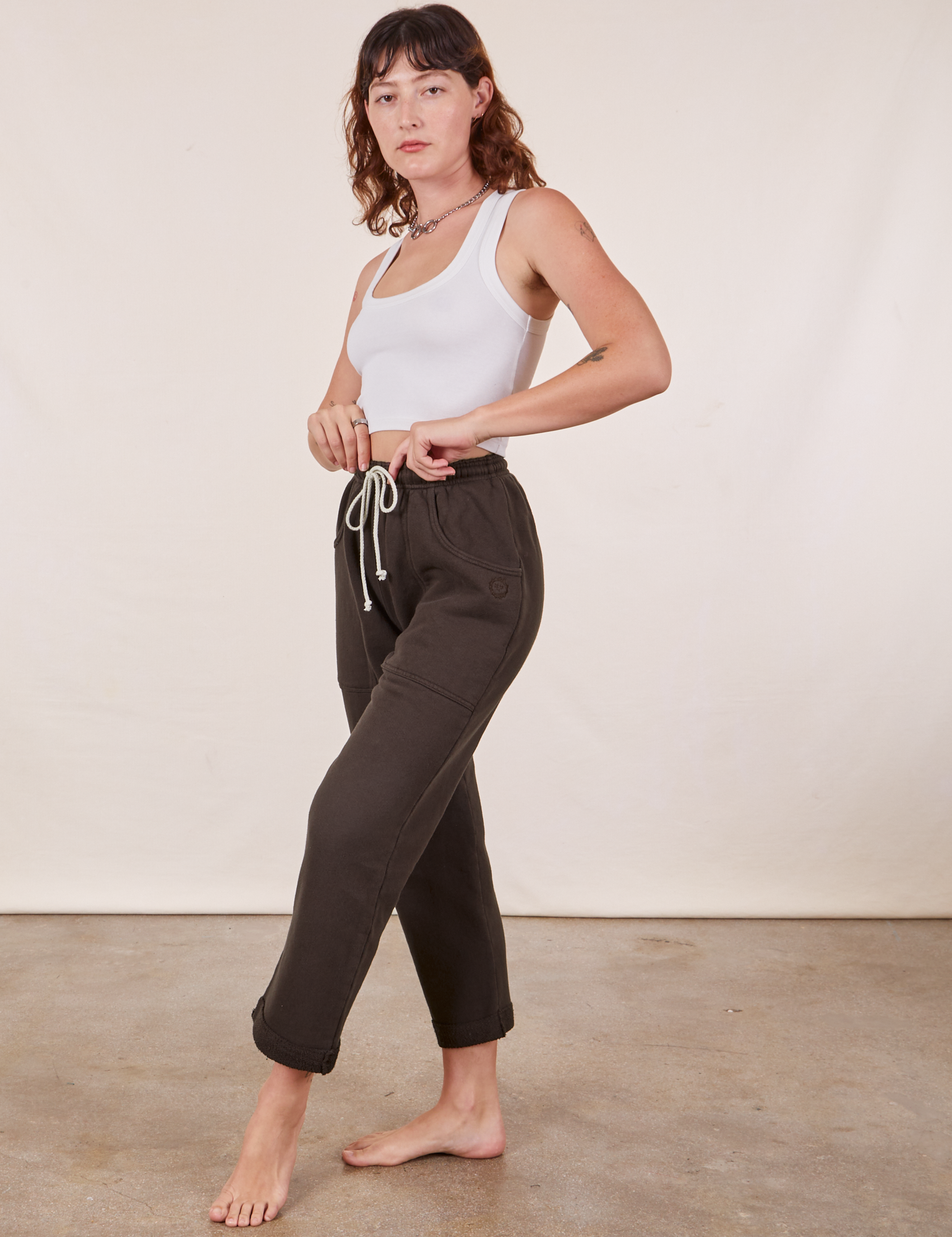 Angled view of Cropped Rolled Cuff Sweatpants in Espresso Brown and vintage off-white Cropped Tank Top on Alex
