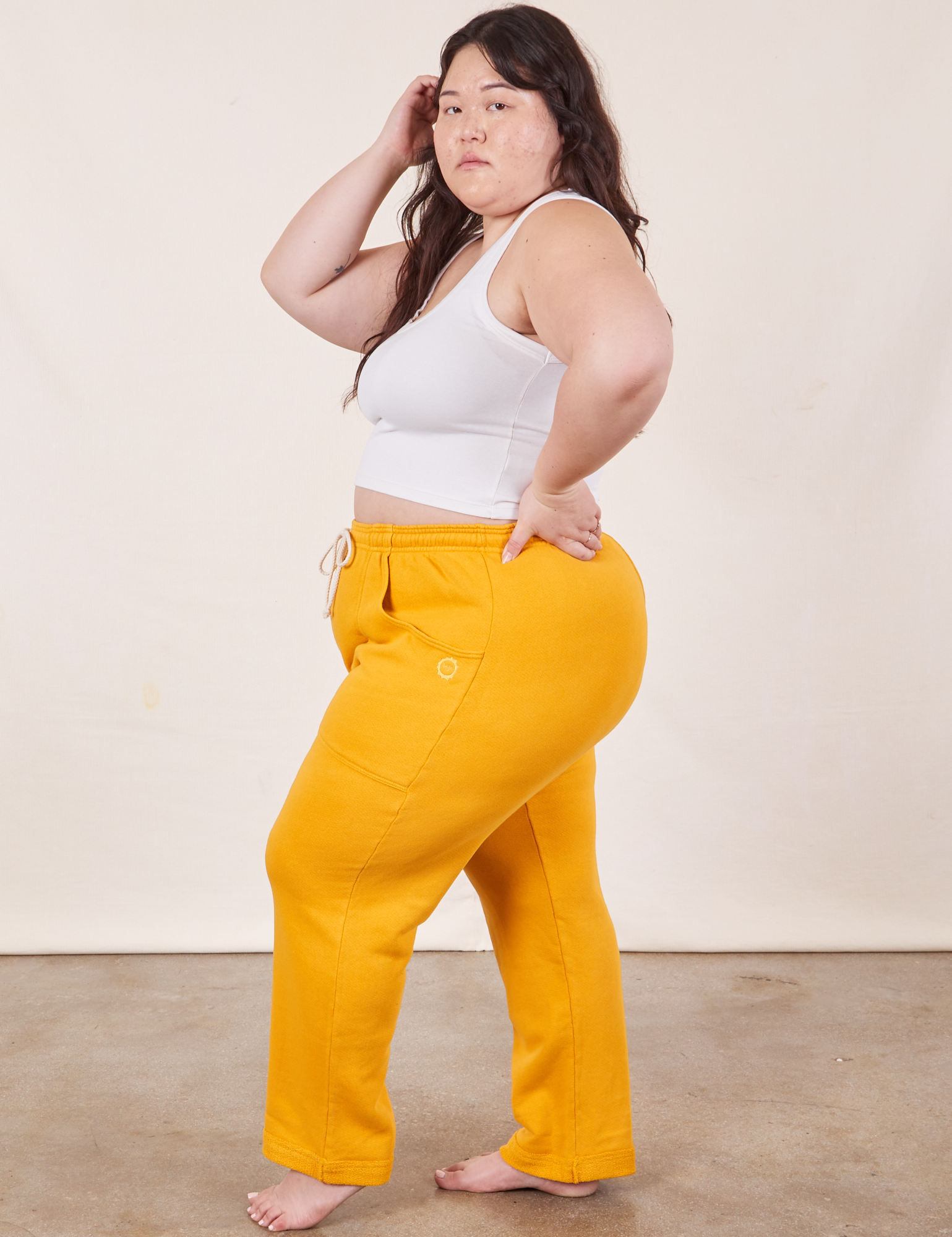 Side view of Cropped Rolled Cuff Sweatpants in Mustard Yellow and vintage off-white Cropped Tank Top on Ashley