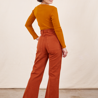 Back view of Western Pants in Burnt Terracotta paired with burnt orange Long Sleeve V-Neck Tee worn by Soraya